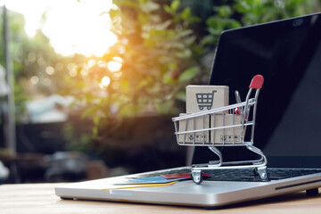 Shopping online. Credit card and cardboard box with a shopping cart logo in a trolley on laptop keyboard. Shopping service on The online web. offers home delivery