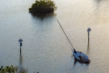 Half sunken sailing yacht capsized on shallow bay waters after hurricane Ian in Manasota, Florida