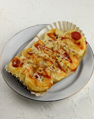 bread with sausage meat and spicy sauce, served on a white plate