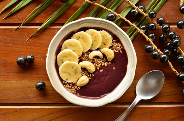 Acai smoothie bowls with banana, cashew and linseed on wooden background top view