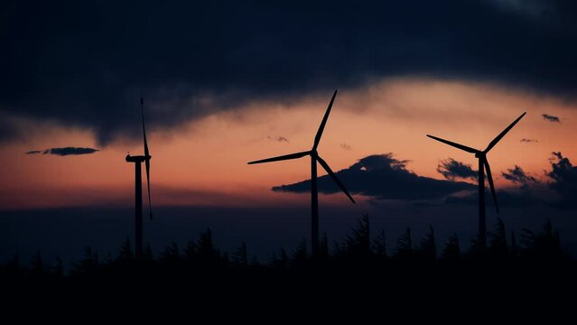 Time lapse of dark clouds moving over wind turbines in the evening. Power generator plant for renewable green energy production on hill. Occitanie, France.