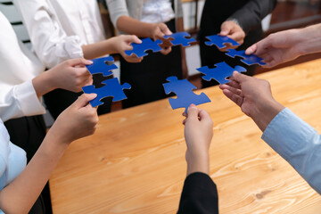 Multiethnic business people holding jigsaw pieces and merge them together as effective solution...