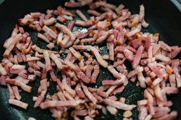 Bacon cut in dices being fried and cooked on a pan