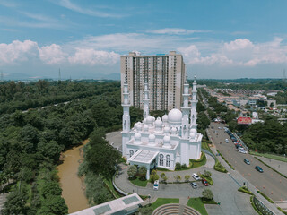 Aerial photo of a grand mosque in the heart of the city, flanked by two apartment buildings,...