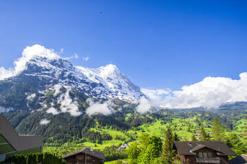 Fototapeta na wymiar Beautiful shot of cabins in a valley under the snowy Alps in Grindelwald, Switzerland