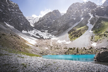 Mountain panorama, landscape with rocky peaks and blue turquoise lake Ziyorat in the Fan Mountains in Tajikistan, on a sunny summer day