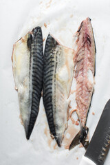 Overhead view of raw mackerel fish being filleted on parchment, filleted scomber fish on white parchment, nigerian scomber fish, fish for keto diet