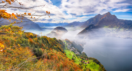 Breathtaking autumn view of Stansstad city and Lucerne lake with mountaines and fog.