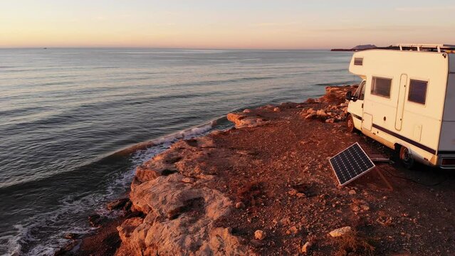Aerial view. Charging battery at camper car. Caravan with portable solar photovoltaic panel camping on sea coast in Spain.