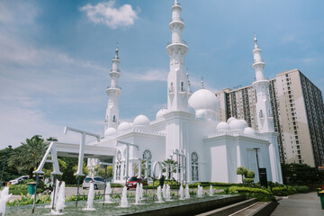 Stunning photo of a grand mosque taken from its courtyard, set against a clear sky, capturing the...