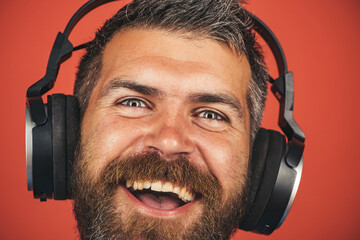 Closeup portrait of smiling man listening music with headphones. Handsome bearded hipster in...