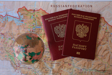 Fototapeta na wymiar Two international red passports of the Russian Federation on the world map. crystal transparent glass ball. planet of Earth. Travelling around the world. 2 Russian national documents on card backdrop