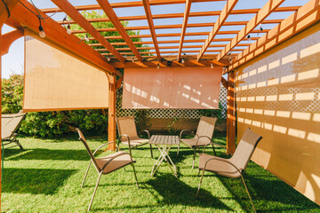 Cozy outdoor seating under a wooden pergola with ambient lighting in a home garden. - 794441308