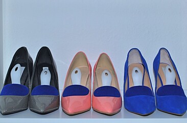 three pairs of women's high heel shoes on a white shelf