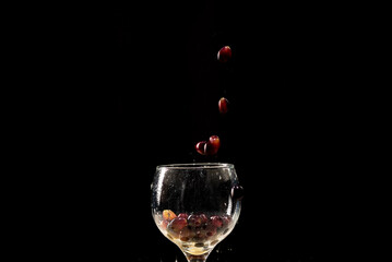 Red grapes falling into a clear glass goblet.