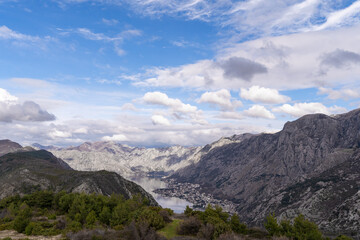 Fototapeta premium A small town on the shores of the Gulf of the Adriatic Sea in a bay in the middle of the Balkan mountains against a background of blue sky and lush clouds.