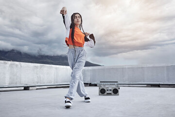 Girl, dance and hip hop outdoor on city rooftop with music, speaker and cool gen z streetwear fashion. Woman, moving and dancer with creative energy on apartment balcony and urban style or freedom