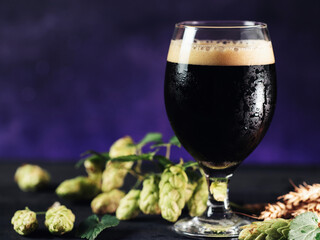 Beer Stout glass on the table with cones of hops