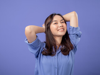 Portrait of an Indonesian Asian woman, wearing a blue shirt, smiling with her hands behind her...