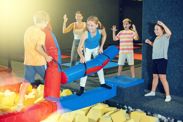 Obraz premium Children having funny wrestling by inflatable logs with his friends in indoor amusement playground