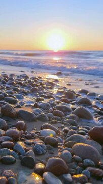 sunset over the sea with rocks on the beach