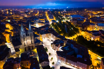 View from drone of impressive Burgos Gothic Cathedral on background of illuminated cityscape at night, Spain..