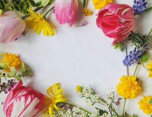 Holiday concept. Postcard, place for text. Tulips, lilacs and other spring flowers on a white background around a white sheet of paper. Frame, space for text, background, copying