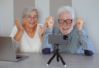 Video call concept. Elderly couple sitting at home talking remotely with family or friends on...
