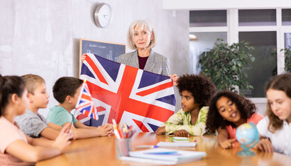 in geography lesson, students carefully listen to woman teacher who talks about Great Britain