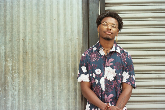 portrait of young black man standing next to wall outside
