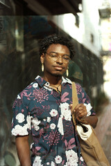 portrait of stylish young man standing outside with bag