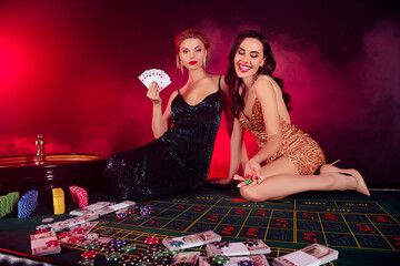 Photo of gorgeous chic people girls sitting poker table throw dice have winning strategy in misty nightclub