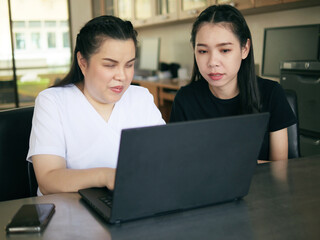 Asian women co-workers in workplace including person with blindness disability using laptop computer with screen reader program for visual impairment people. Disability inclusion at work concepts