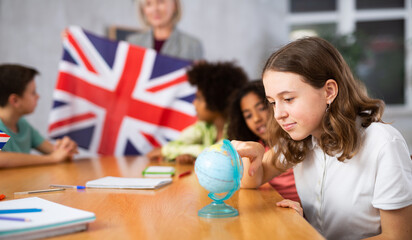in geography lesson, students carefully listen to woman teacher who talks about Great Britain