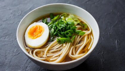 asian noodle soasian udon noodle soup with egg and greens a bowl of asian udon noodle soup garnished with a soft boiled egg green onions and herbs presented on a black background up