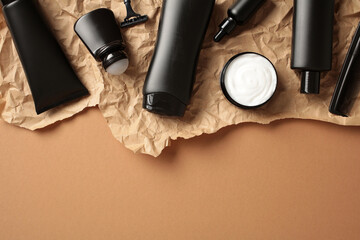Elegant black men's cosmetic bottles with hair care products on a brown background. Flat lay, top view.