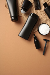 Clean black cosmetic bottles with men skin care products on craft paper on brown background. Flat lay, top view.