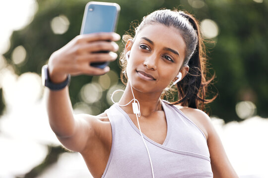 Selfie, earphones and woman athlete in nature for health, wellness or body workout listen to music. Smile, outdoor and Indian female person with photography picture for exercise or training in park.