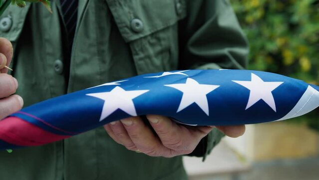 Folded Flag In Commemoration Of American Fallen Held In Hand