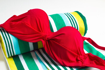 A red bikini on a rolled beach towel, summer concept