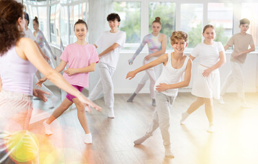 Teenage boy rehearse hip hop dance repeats movements of unrecognizable instructor performance with peers. Preparing for performance of choreographic team, practicing skills, repeating exercises