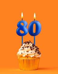 Blue candle number 80 - Birthday cupcake on orange background