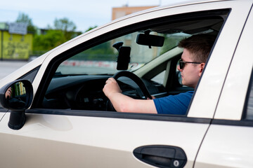 Driver wearing sunglasses, man driving a car, person in car, young driver