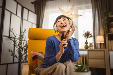 Fototapeta na wymiar Mature japanese woman with headphones listen music on mobile phone