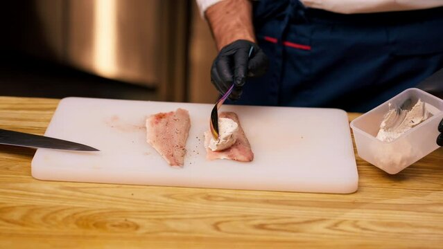 close-up in a professional kitchen spreading a fish fillet with special white sauce with a spoon