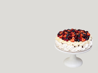 Meringue Pavlova cake with whipped cream and fresh berries isolated on grey background. Horizontal...