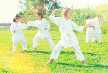 Girl in white kimono during training karate exercises at summer outdoors