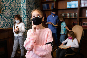 Children in protective masks are thinking about solving a problem in the quest room
