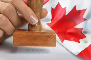 Double exposure of woman stamping visa document and Canada flag, closeup