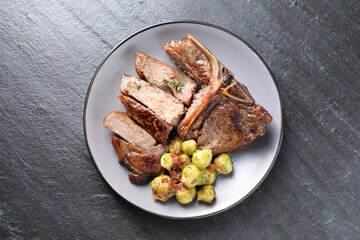 Delicious fried beef meat, vegetables and thyme on black table, top view